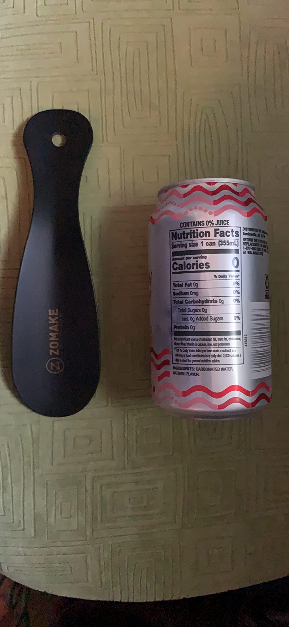 ZOMAKE shoe horn in use showing scale comparison with soda can demonstrating compact size