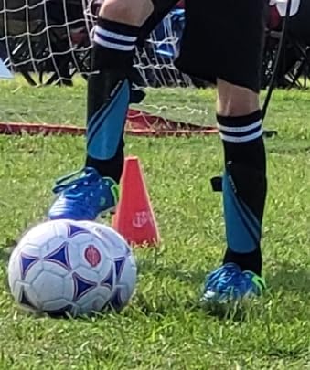Close-up view of DREAM PAIRS soccer cleats showing synthetic leather upper and lace design
