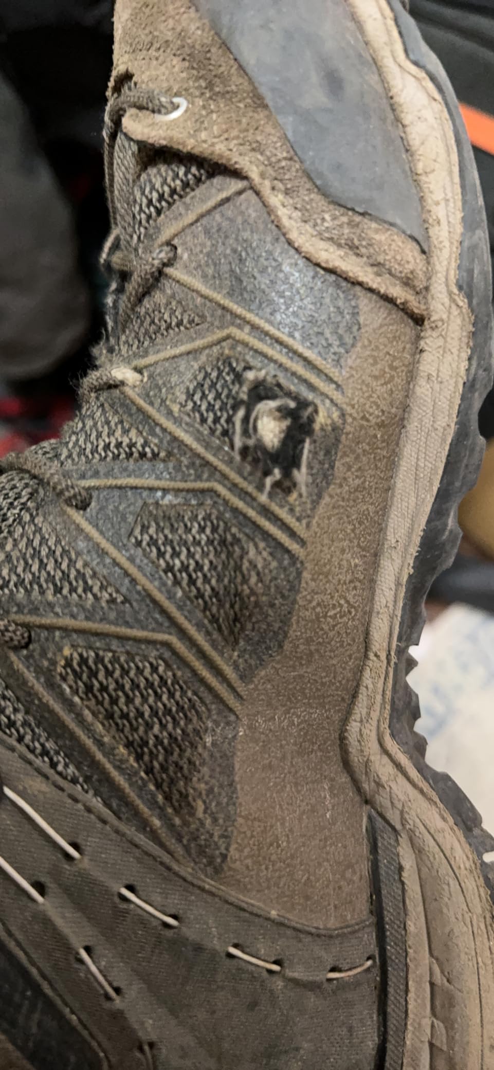 Hiking boot showing hole in side material from trail debris impact