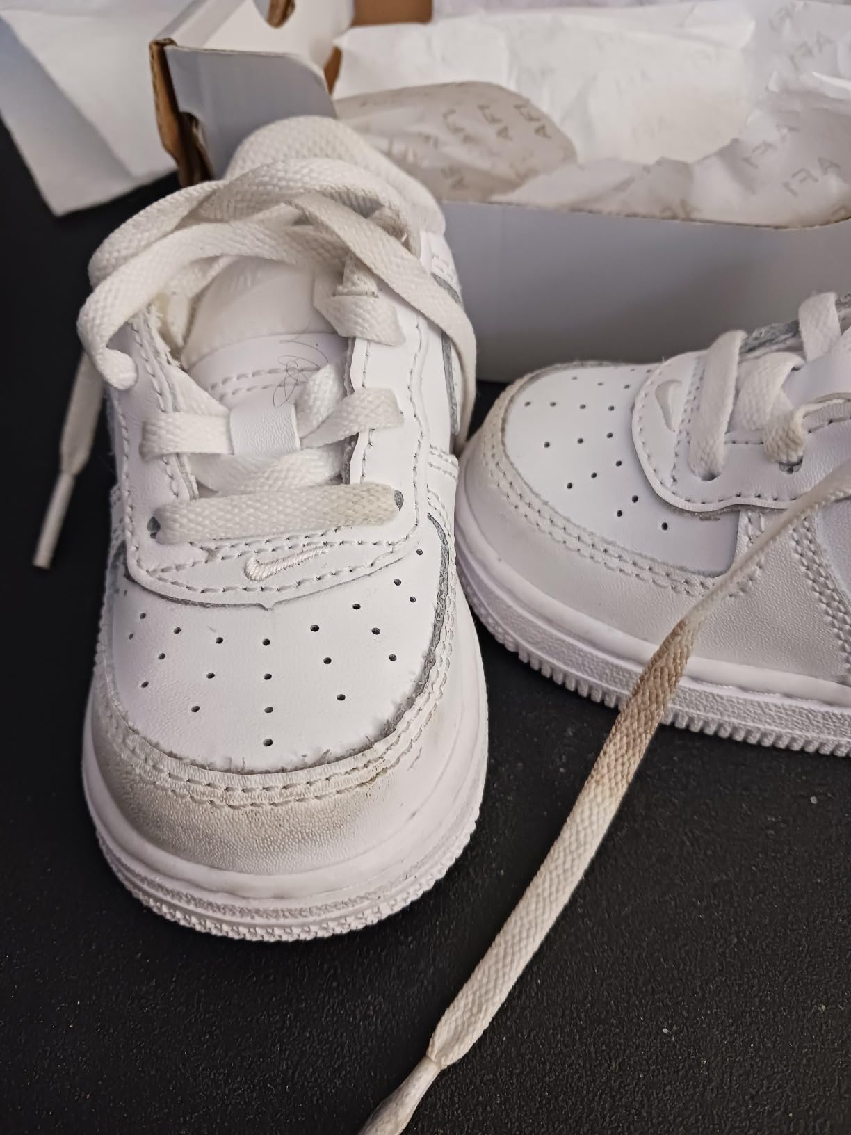 Nike Air Force 1 showing quality control issues with dirty laces and scuffed toe area out of box