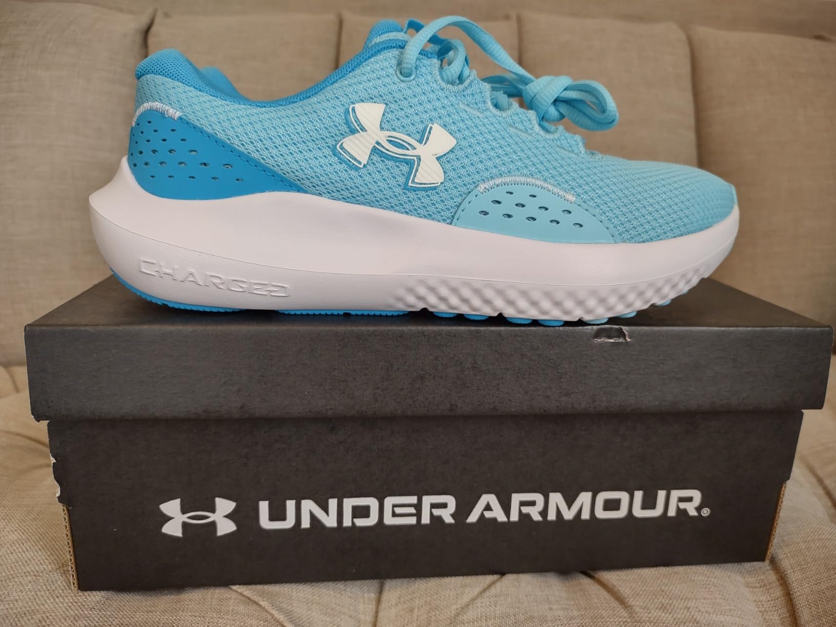 Under Armour Charged Surge 4 showing multiple colorways including black, white, and pink options with EVA midsole technology