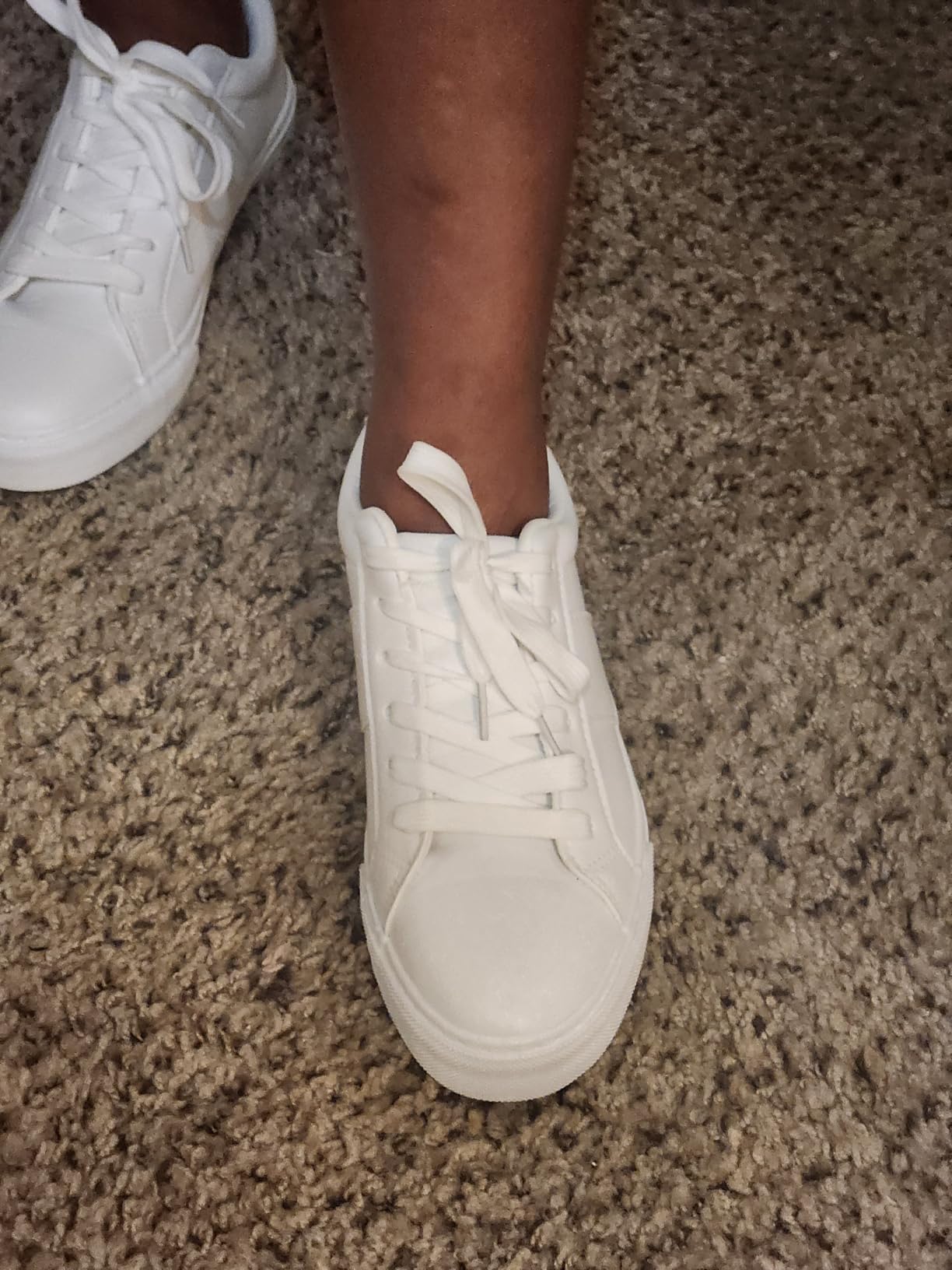 Close-up view of Adokoo sneakers showing PU leather texture and stitching details on white casual shoes