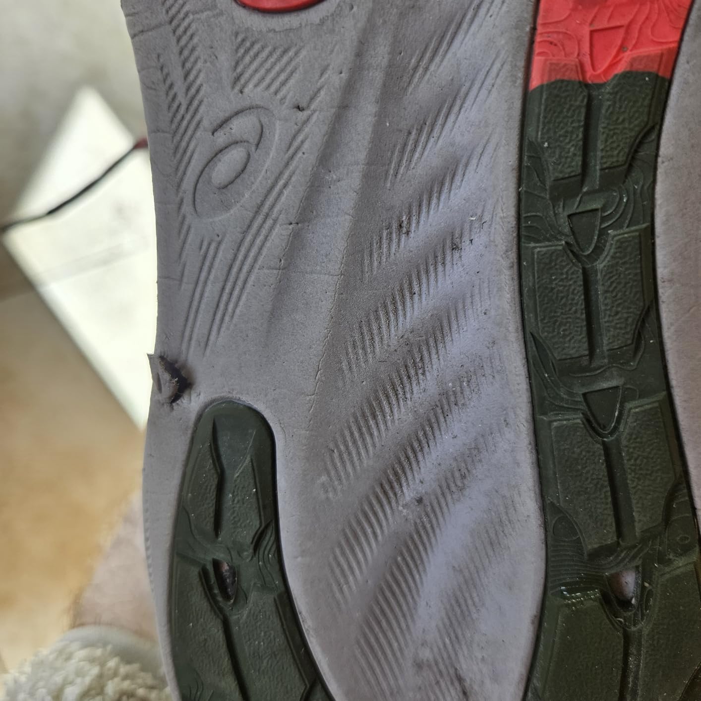 ASICS Gel-Nimbus 26 sole showing wear pattern after trail running with visible puncture damage