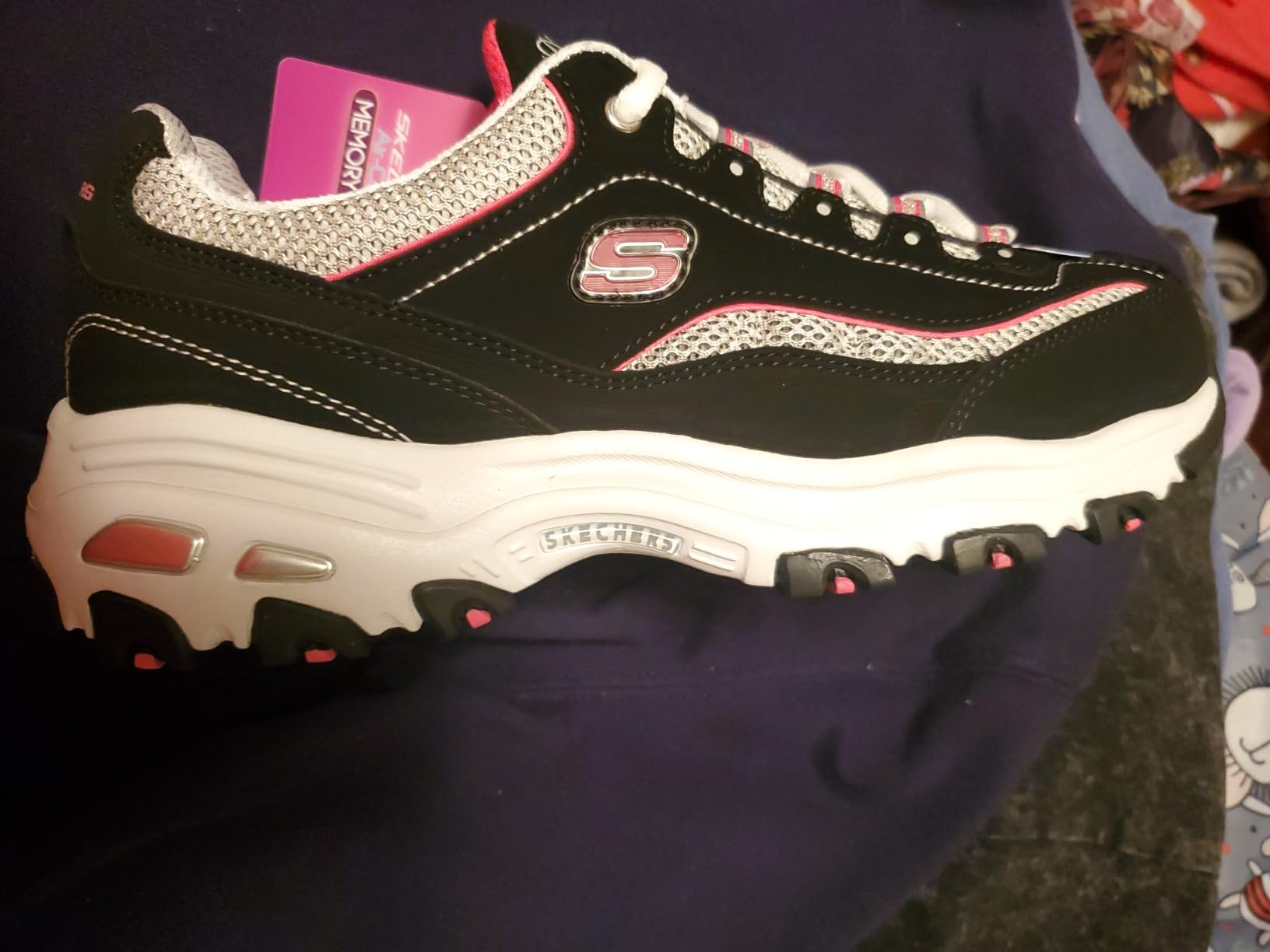 Top-down view of the Skechers D'Lites showing the padded tongue and lacing system, with extra pink laces nearby.