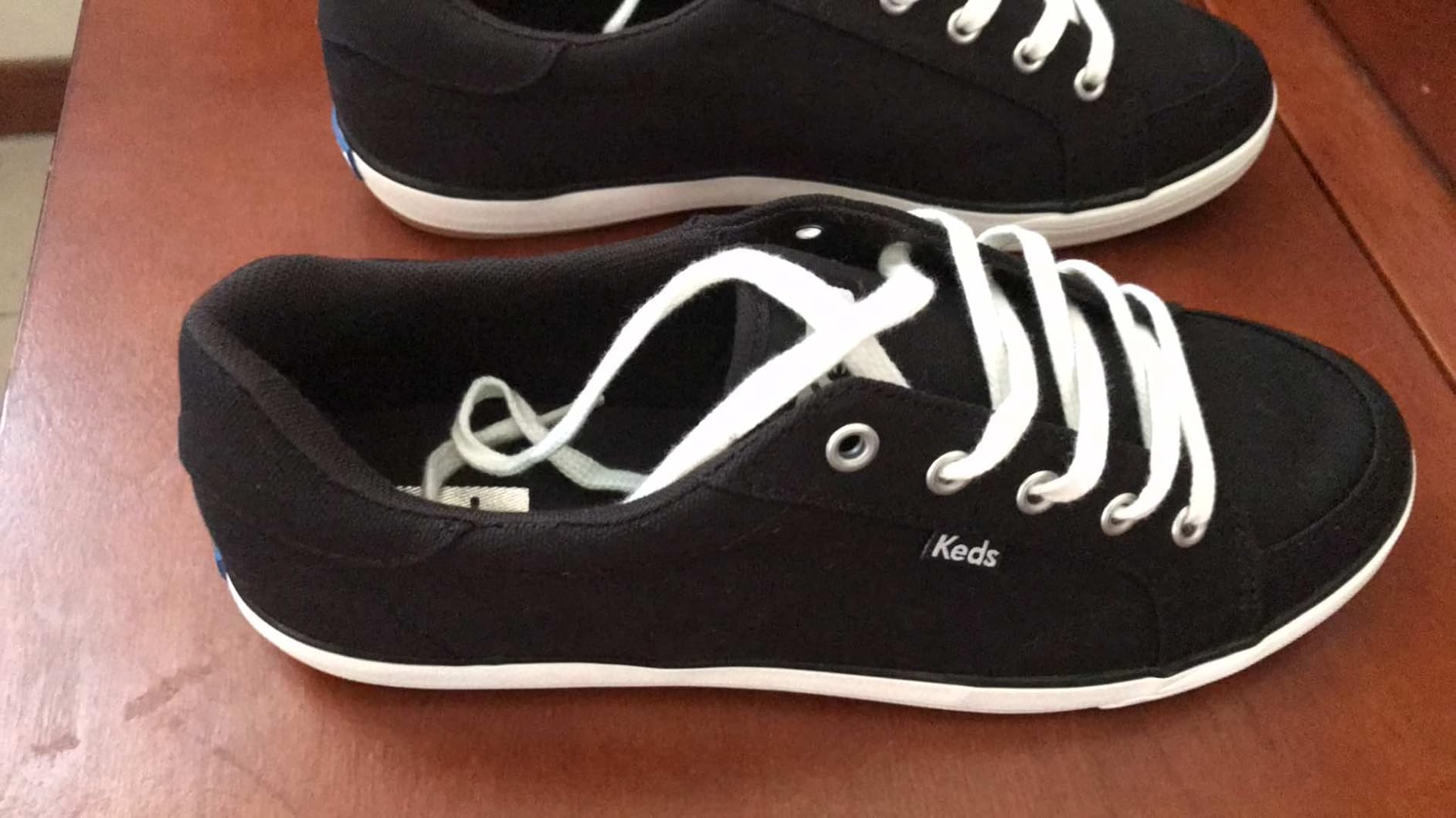 Close-up of Keds sneaker side profile showing chambray canvas texture and navy heel detail