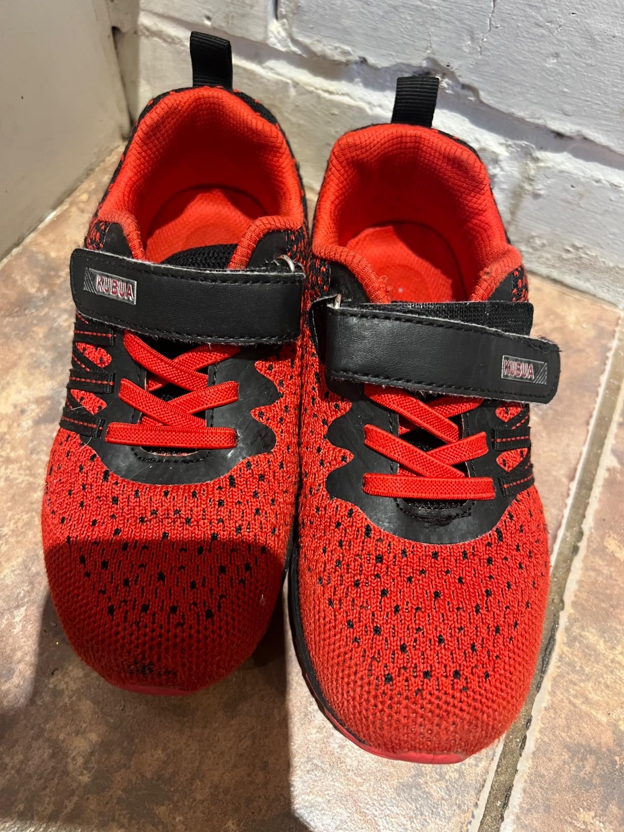Close-up of KUBUA kids sneakers showing hook and loop Velcro strap system and padding details