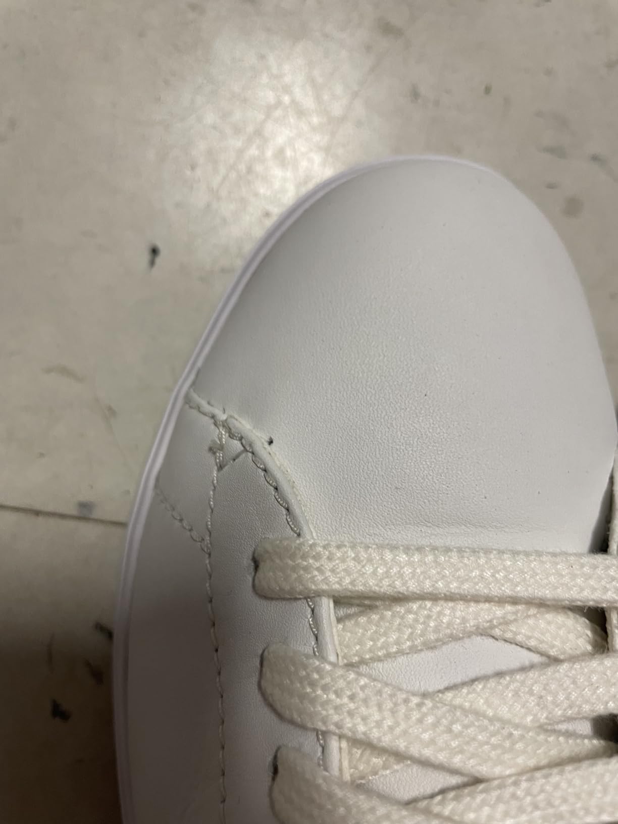 Quality control issues showing uneven stitching and construction defects on Cole Haan sneakers