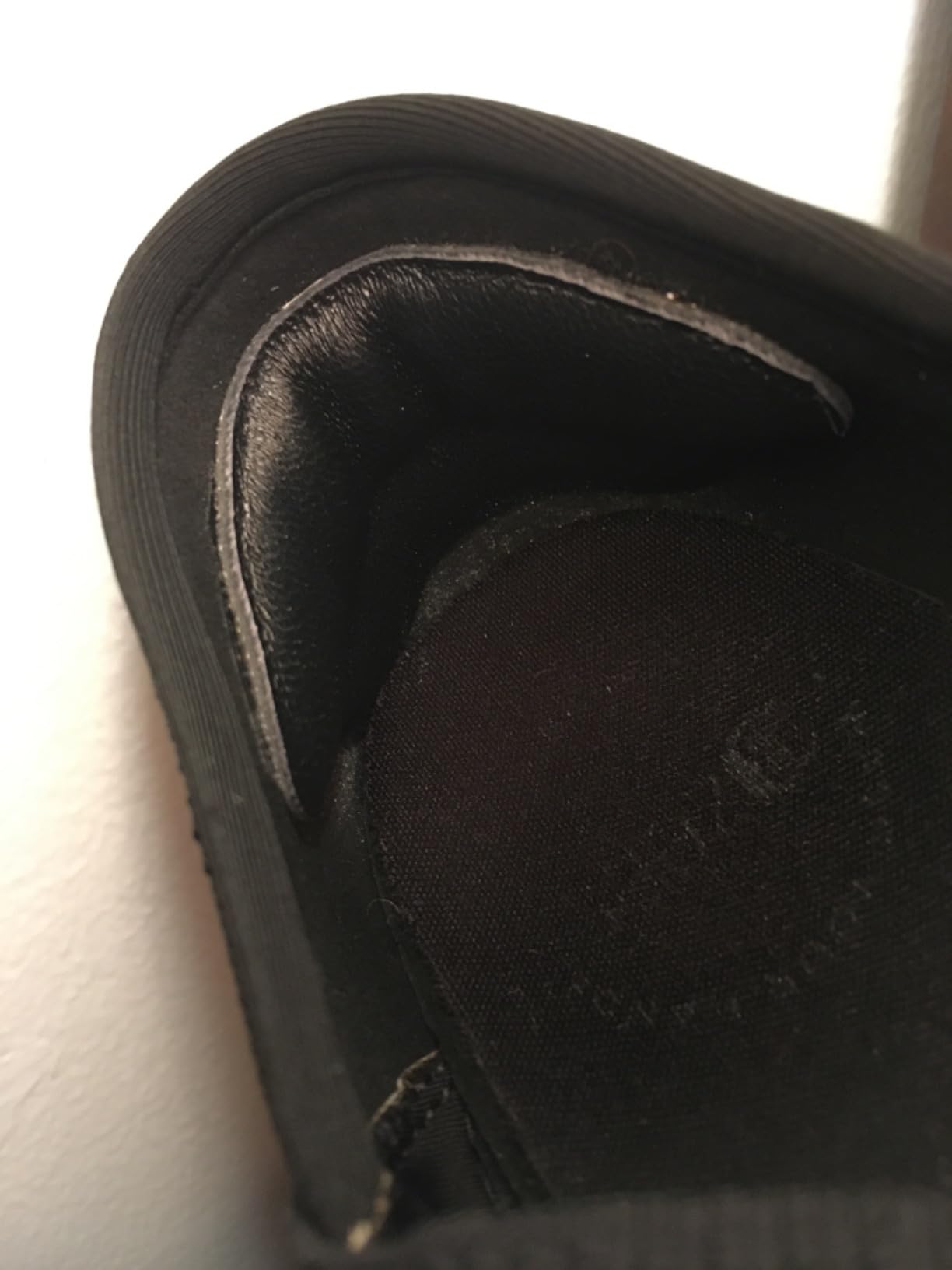 Black heel pad installed in black shoe showing adhesive placement and thickness profile