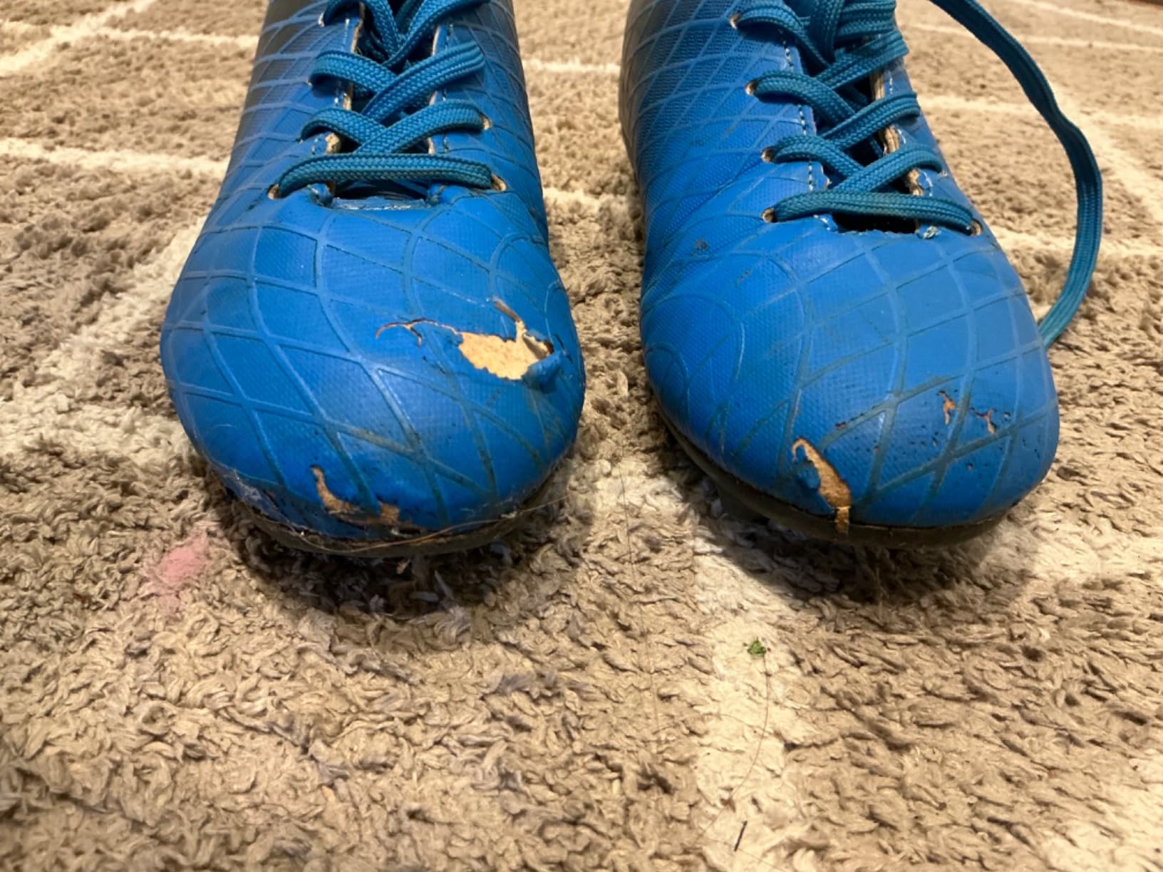 Damaged kids soccer cleats after a few practices showing outsole separation