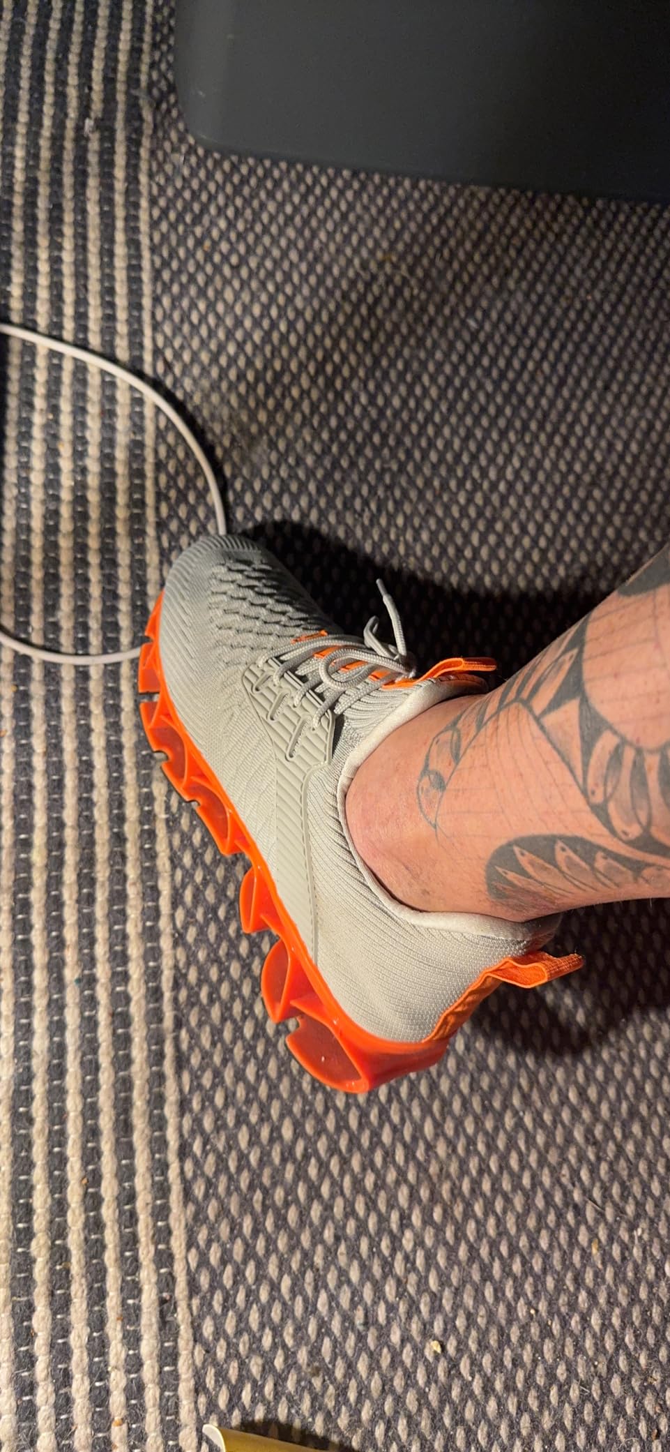 Close-up detail of orange and gray slip-on sneaker showing knitted mesh upper and design elements